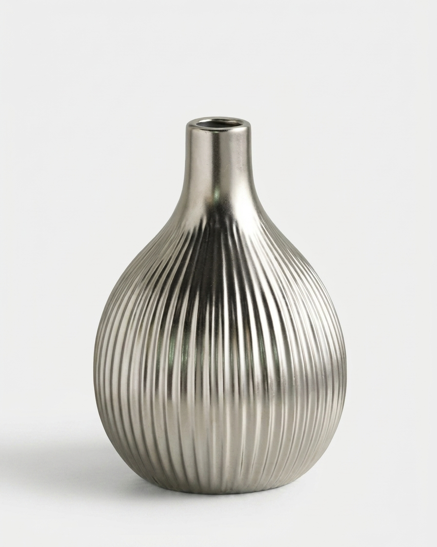 A metallic silver vase with a ribbed, vertically fluted texture, photographed against a clean, light gray background.
