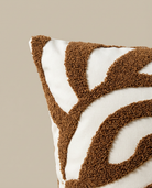 Close-up of a decorative pillow with brown leaf pattern on a beige background