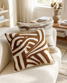 Decorative pillow with brown and white pattern on a beige sofa in a living room setting.