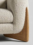 Close-up of a textured beige sofa with wooden armrests on a light gray background
