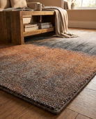 Gradient area rug on a wooden floor with a wooden side table and books in the background.