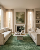 Modern living room with beige sofas, a green rug, and decorative elements.