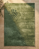 Green rug on a beige tiled floor with a leaf shadow