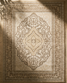 Decorative beige rug with intricate patterns on a wooden floor.