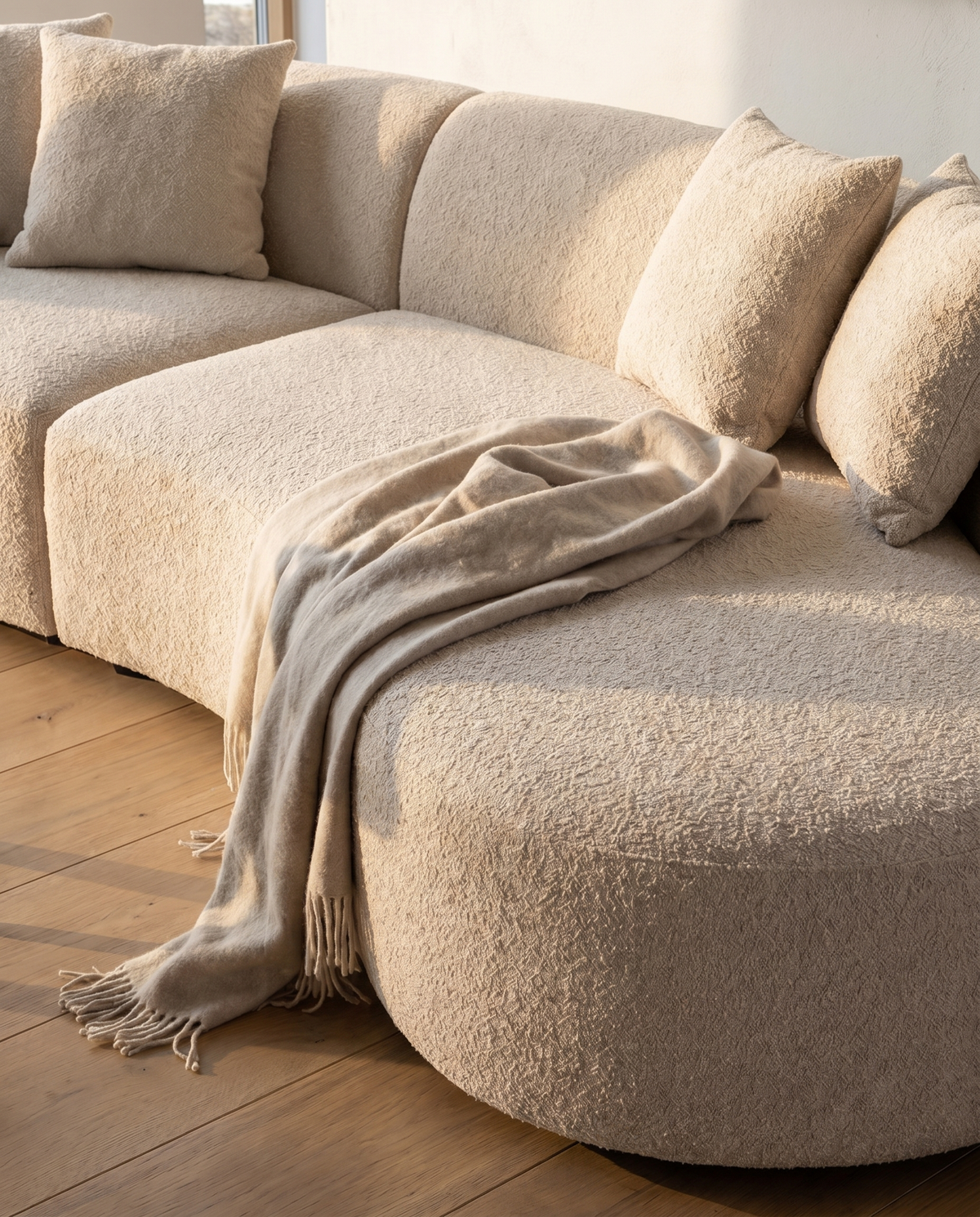 Koln Curved Sofa in Frosted Bone, styled on a wooden floor with cushions