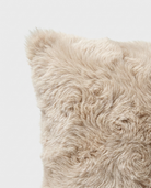 Close-up of a fluffy beige pillow on a light gray background