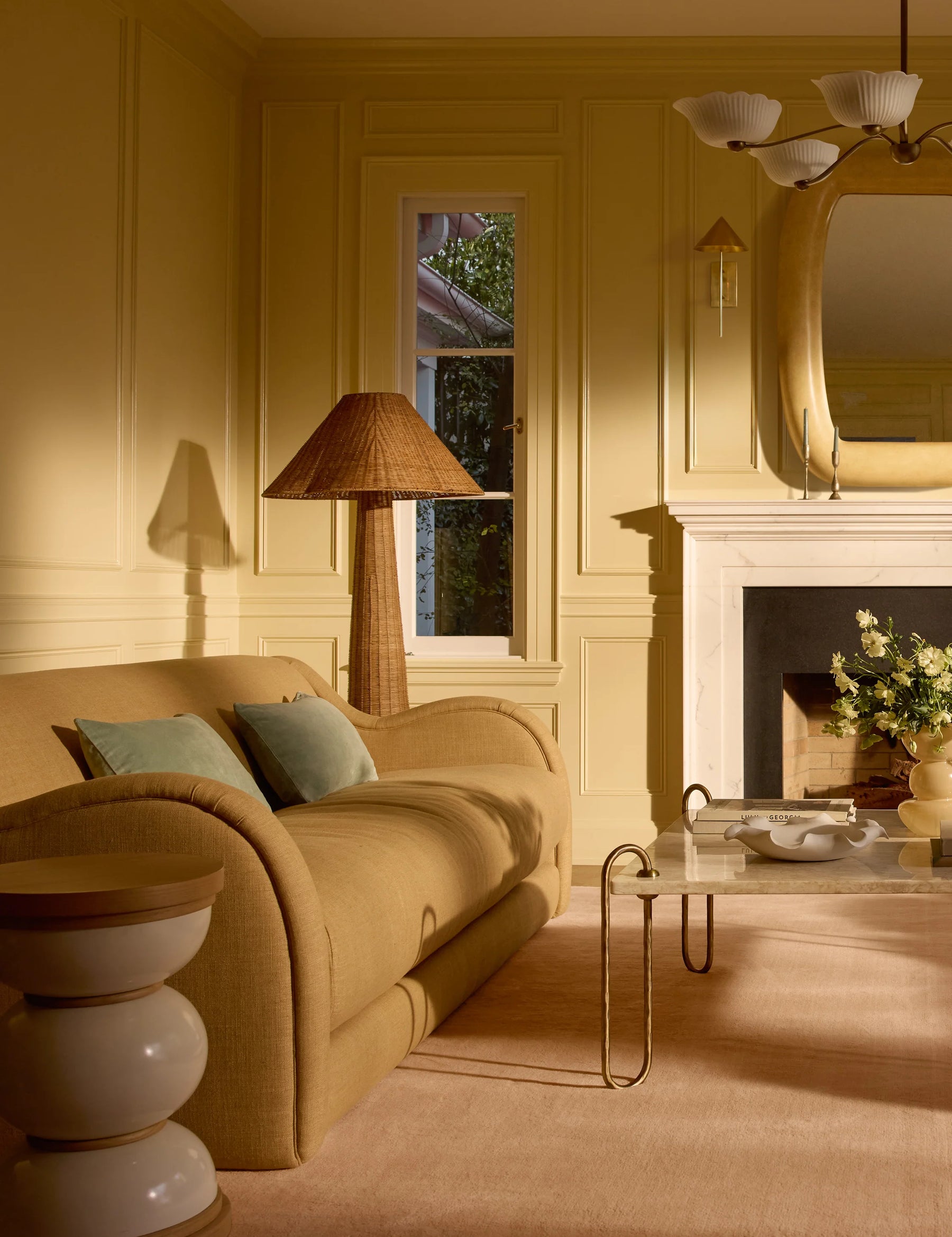 Lova Faux Fur Pillow in Dune Mist, styled in a living room with lamp and fireplace