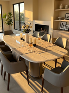 Dining room with a long table set for dinner, chairs, and a fireplace.
