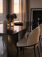 Dining room with a dark wooden table and beige chairs, candles, and decorative items.
