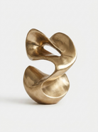 An abstract sculptural vase with a brushed metallic gold finish, photographed on a clean, light gray background.
